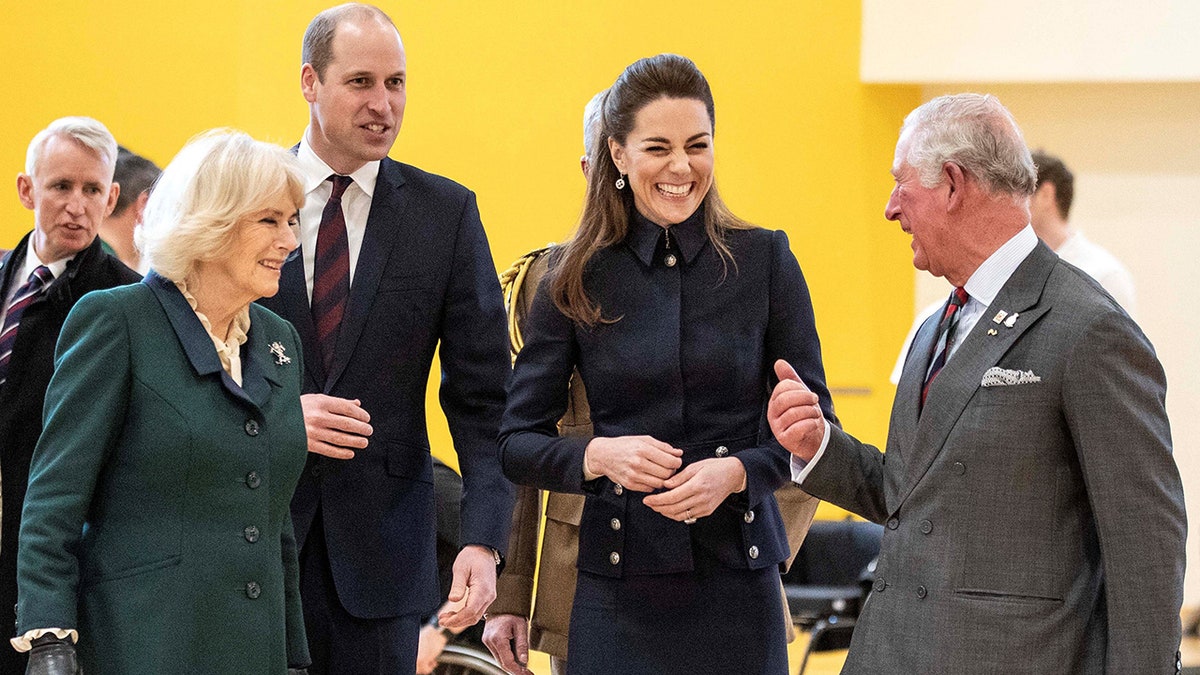 Kate Middleton laughing with King Charles III as Prince William and Queen Camilla look on.