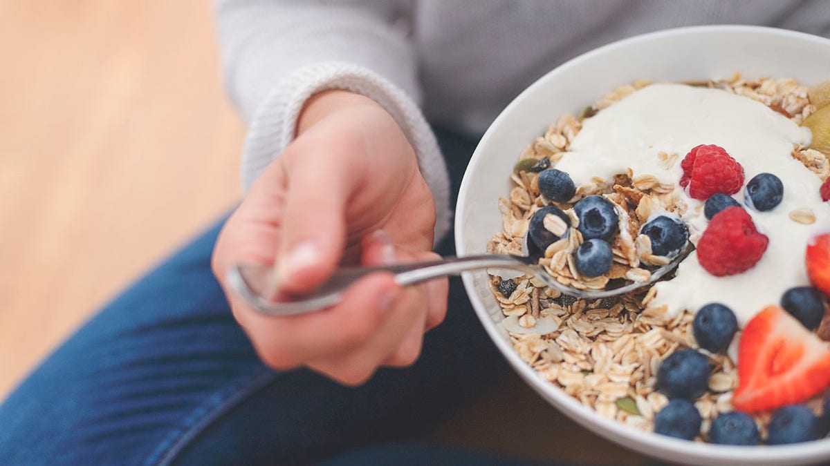 healthy breakfast bowl includes strawberries, blueberries, granola and yogurt.