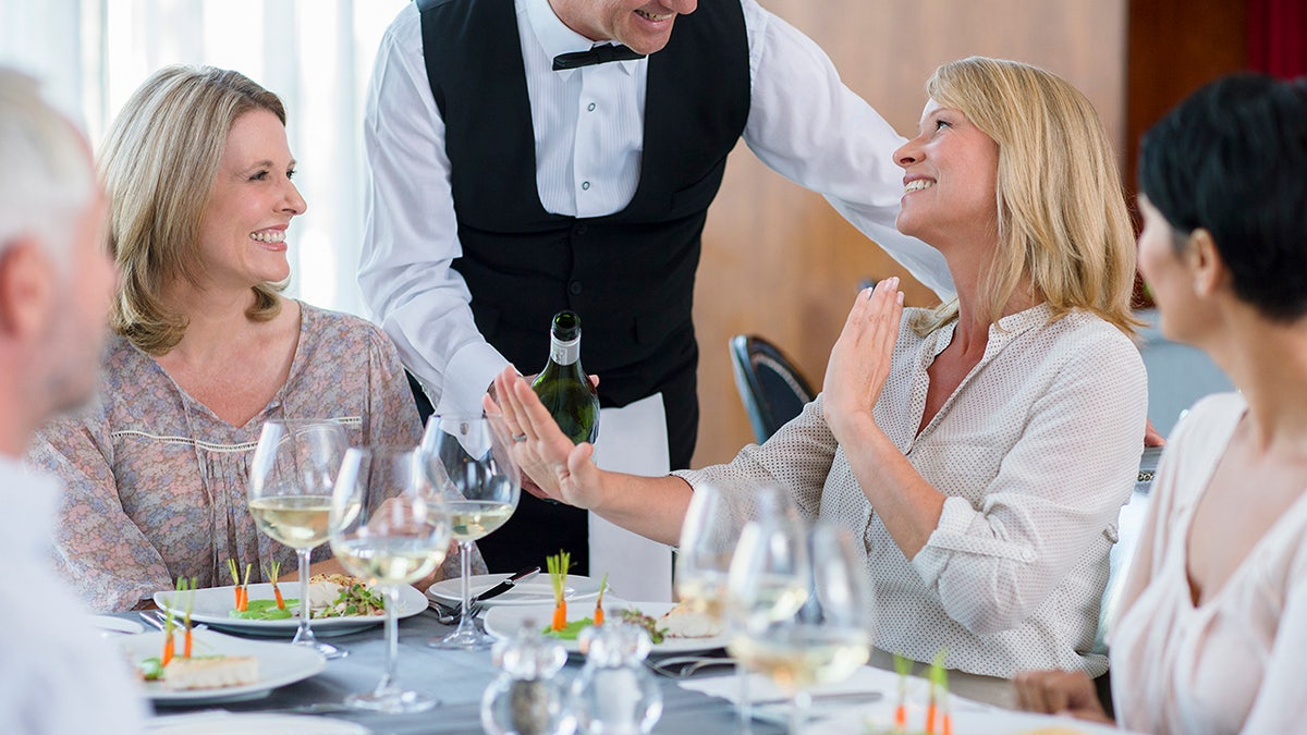 Waiter offers wine to a woman who refuses