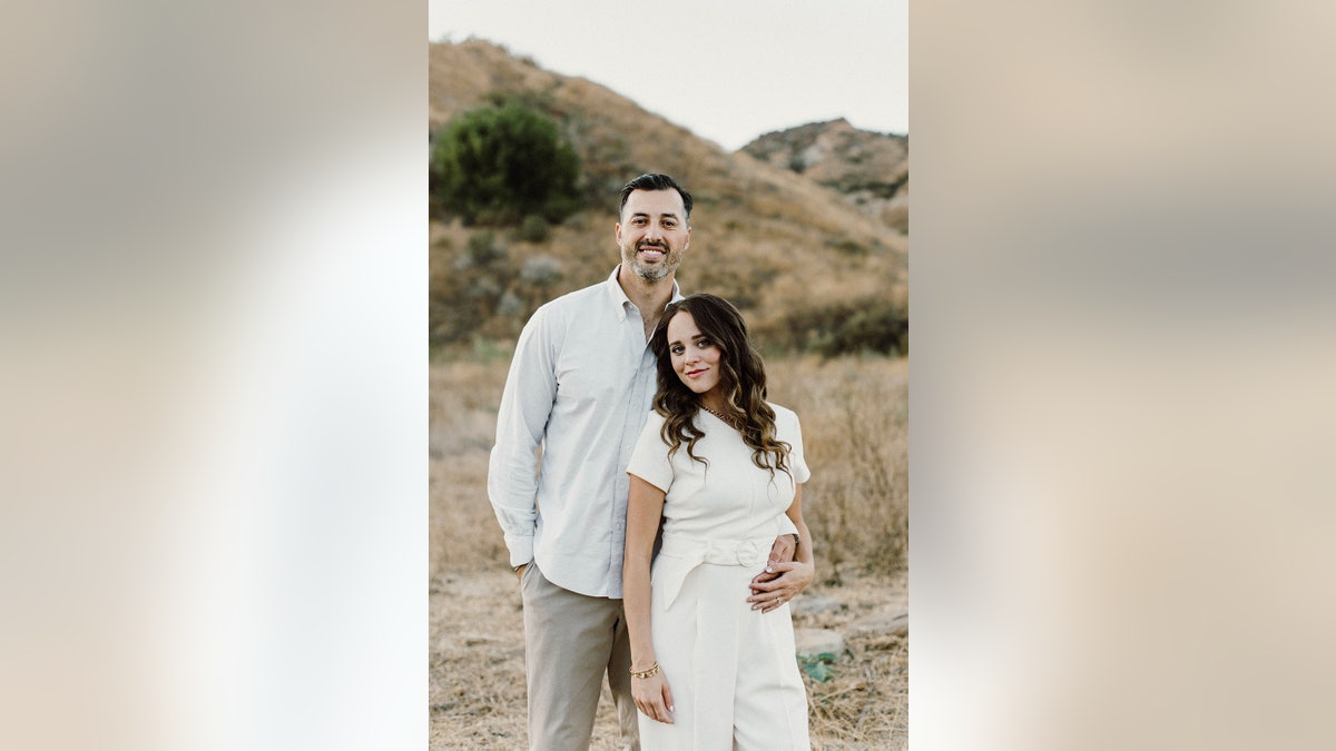 Jinger Duggar Vuolo dressed in white being held by her husband Jerem