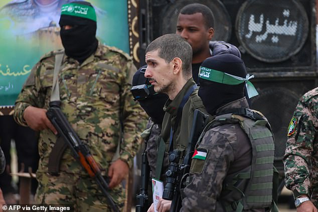 Palestinian Hamas fighters escort Israeli hostage Or Levy on a stage before handing him over to a Red Cross team in Deir el-Balah, central Gaza, on February 8, 2025