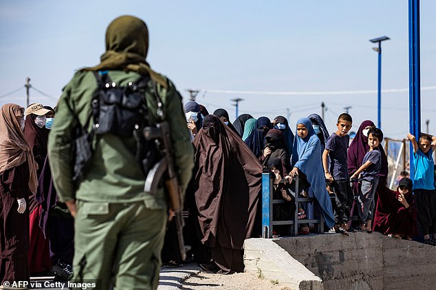 People stand in a queue at Camp Roj, where relatives of people suspected of belonging to the Islamic State (IS) group are held in Syria's northeastern Hasakah province on October 8, 2023