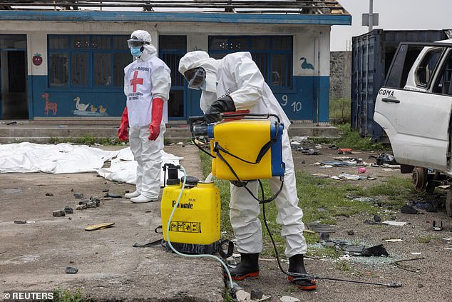 Red Cross volunteers mix chlorine disinfectant during the removal of bodies who died in a jailbreak and fire at Munzenze central prison