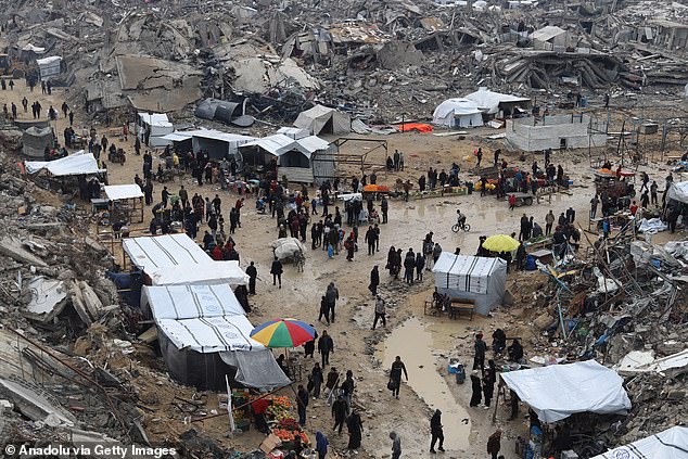 An aerial view shows Palestinians walk through the ruins of destroyed buildings in Jabalia refugee camp, northern Gaza Strip, on February 5