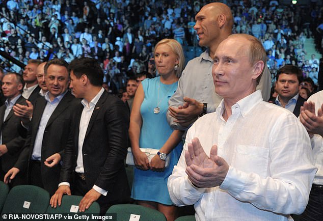 Russia's President Vladimir Putin (R) applauds after watching a mixed martial arts fight at Ice Palace in Saint-Petersburg, late on June 21, 2012, with former world heavyweight boxing champion, Nikolai Valuev standing behind